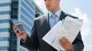 Imagem horizontal de um empresário com calculadora e documentos fiscais ao fundo, cores sóbrias na cor azul, cinza e branco, transmitindo seriedade e gestão financeira, destacando a palavra-chave descobrir verdade tributação dividendos.