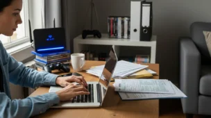 Pessoa usando laptop em ambiente doméstico, com elementos de tecnologia e papéis fiscais, simbolizando a exigência de CPF e CEP Netflix exige CPF CEP